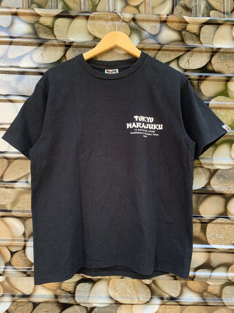 BAPE A Bathing Ape Daruma Graphic Tee (Category: Tshirts & Polo Shirts ) located in Aloran. Submitted by chester78864 (Listing ID 1461285552, Image 2). Description: - Brand: A Bathing Ape (BAPE) - Color: Black - Size: Medium (M) - Design: Features a cool Daruma graphic on the back. - Front Details: A Bathing Ape logo and "Tokyo Harajuku" text. - Ideal for: Streetwear fans and collectors..