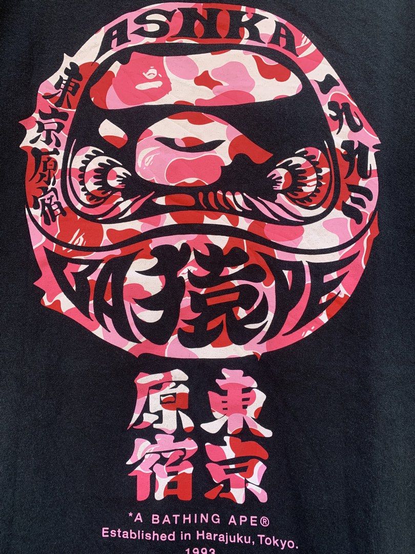 BAPE A Bathing Ape Daruma Graphic Tee (Category: Tshirts & Polo Shirts ) located in Aloran. Submitted by chester78864 (Listing ID 1461285552, Image 3). Description: - Brand: A Bathing Ape (BAPE) - Color: Black - Size: Medium (M) - Design: Features a cool Daruma graphic on the back. - Front Details: A Bathing Ape logo and "Tokyo Harajuku" text. - Ideal for: Streetwear fans and collectors..