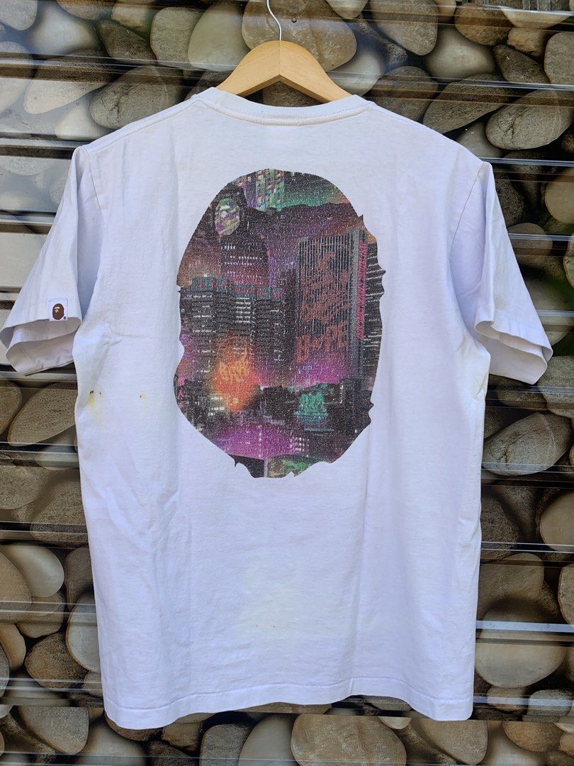 BAPE City Camo Ape Head Tee White (Category: Tshirts & Polo Shirts ) located in Aloran. Submitted by chester78864 (Listing ID 1461285370, Image 2). Description: - White BAPE T-shirt -stain issue and minor flaw on print - Iconic Ape Head graphic with city skyline print - Graphic on both front and back - Size: Medium (M) - Essential for any streetwear collection.