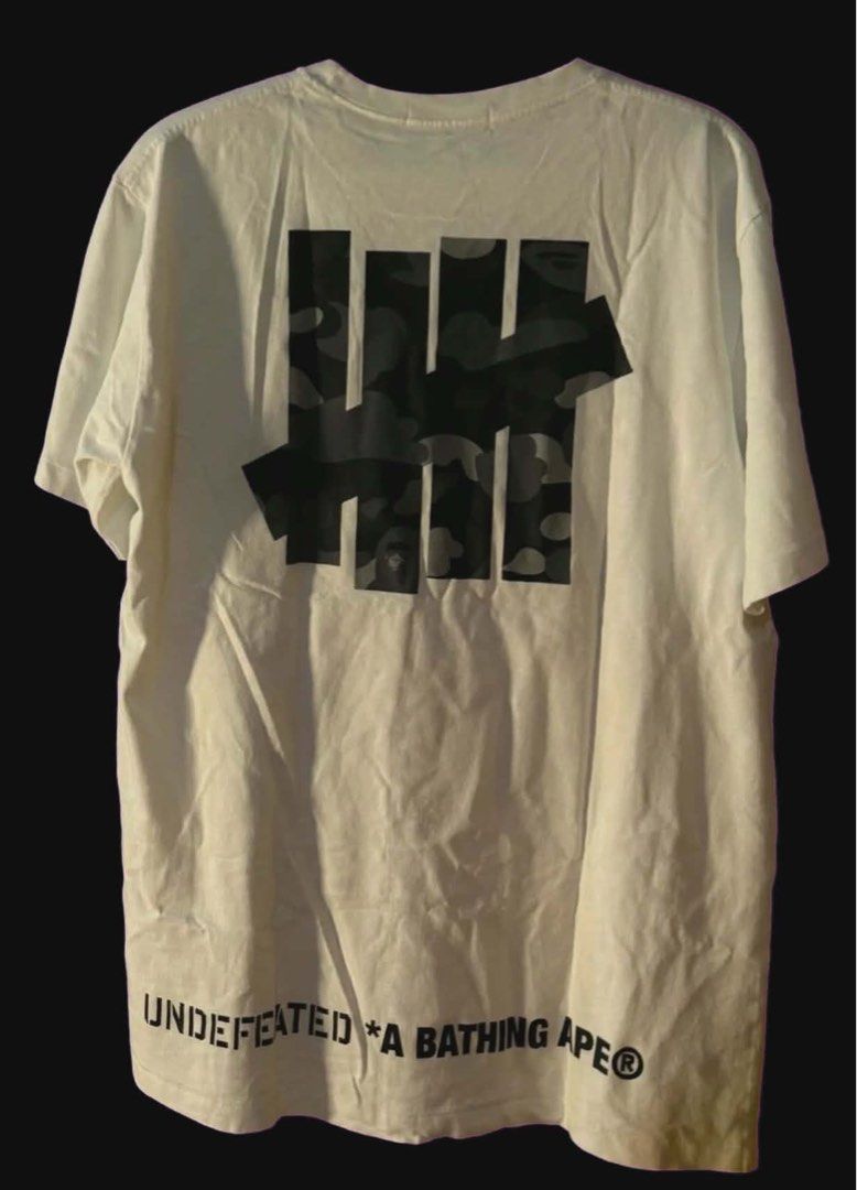 BAPE x Undefeated Camo Ape Head Tee White (Category: Tshirts & Polo Shirts ) located in Manila. Submitted by ruruchanexe (Listing ID 1461280126, Image 2). Description: BapexUndefeated XL(21x28). Authentic Shipping: Lalamove(Around Manila), JNT Honest Issue: Almost flawless, dot chip print front and back..