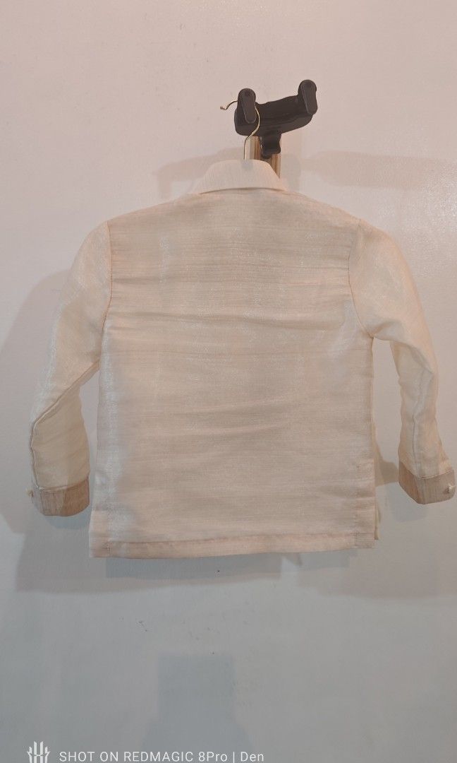 Barong for Kids (Category: Babies & Kids Fashion) located in Manila. Submitted by dentoters (Listing ID 1461135508, Image 2). Description: Measurements: Length - 40cm Width (shoulders) - 30cm Sleeve length - 38cm Description: - Cream-colored Barong Tagalog shirt for boys age 3-4 years old. Features intricate brown and black embroidery on the chest. - Long sleeves with button cuffs. Made from a light, slightly sheer fabric. Ideal for formal events