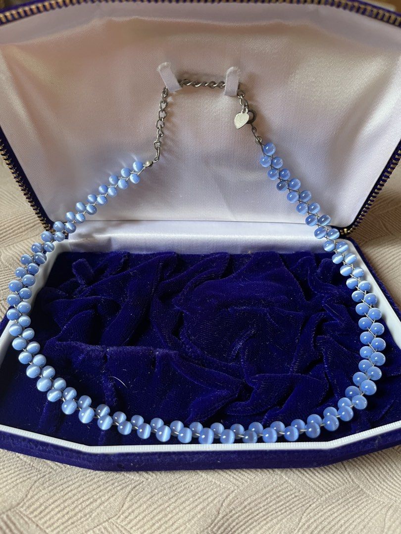 Blue Cat Eye Bead Necklace with Silver Clasp (Category: Necklaces) located in Tandag. Submitted by maryarlale42144 (Listing ID 1461121629, Image 1). Description: - Pretty blue necklace - Features cat eye beads - Strung on a silver-toned chain - Secure lobster clasp closure - Adorned with a small heart charm - Includes a blue velvet jewelry box - Adds a lovely pop of color to any outfit.