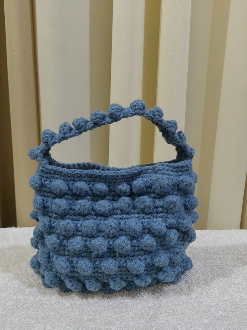 Blue Crochet Bobble Handbag with Handle (Category: Tote Bags) located in Makati City. Submitted by prelovedtreatedwithlove (Listing ID 1461319492, Image 1). Description: - Adorable blue crochet handbag - Unique all-over bobble texture - Sturdy handle for comfortable carrying - Secure snap button closure inside - Compact size, ideal for essentials - Handmade item - Perfect for casual outings and everyday use - no issue.