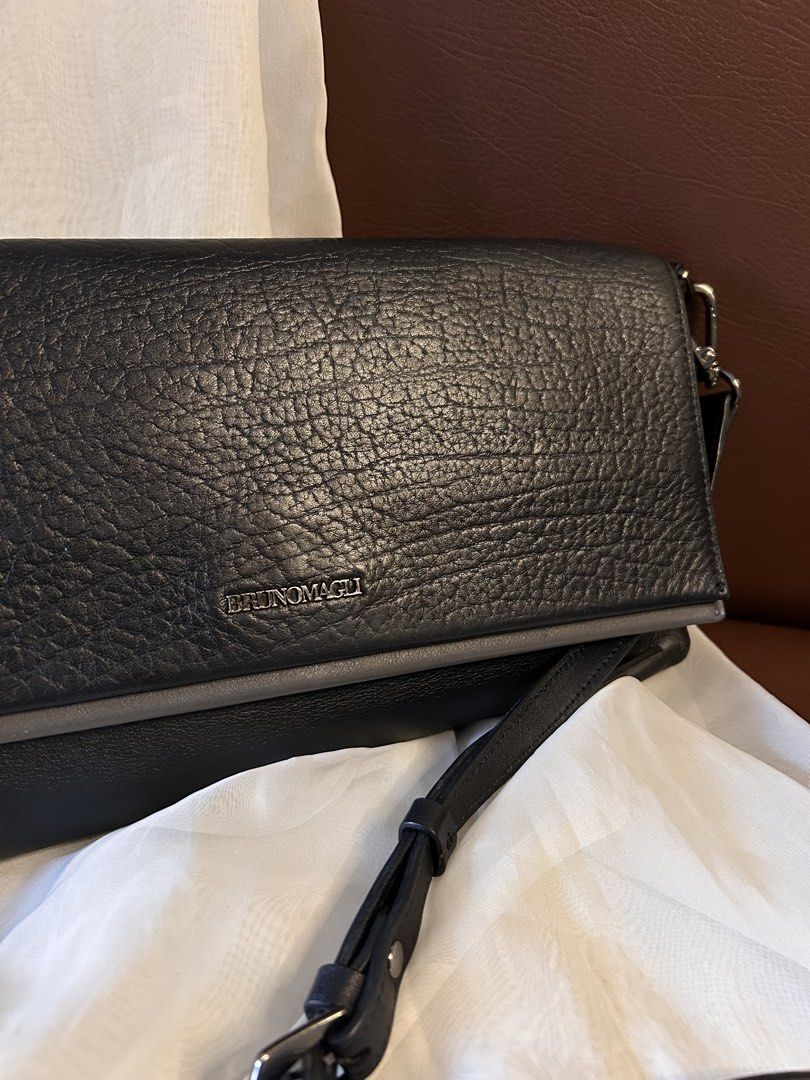 BRUNO MAGLI SLINGBAG (Category: Cross-body Bags) located in Baguio. Submitted by chmlnstudio (Listing ID 1461297925, Image 2). Description: Product Details ✦ Brand: Bruno Magli ✦ Color & Texture: Black pebbled leather flap with smooth charcoal/dark gray accents Hardware & Features: ✦ Dark gunmetal-tone hardware with engraved Bruno Magli branding on the front plate, strap buckle, and clips ✦ Flap closure with secure magnetic snap button ✦ Detachab