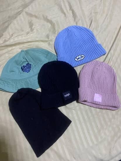 Bundle of 5 beanies - various colors (Category: Hats & Beanies) located in Paranaque City. Submitted by Heyhey0125 (Listing ID 1461320303, Image 1). Description: - Bundle of 5 headwear items - 1 Light blue bucket hat with heart logo - 1 Light blue ribbed beanie with 'la la' logo - 1 Dusty rose ribbed beanie with pink patch - 1 Black ribbed beanie with small tag - 1 Plain knit black beanie.