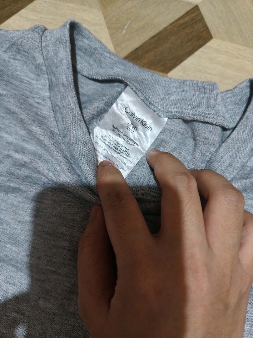 Calvin Klein Grey T-shirt (Category: Tshirts & Polo Shirts ) located in Paranaque City. Submitted by yukigrace12 (Listing ID 1461269355, Image 2). Description: - Grey Calvin Klein T-shirt - Size: Tag says 10/12 - Material: 100% Cotton - Features: Vertical Calvin Klein logo printed on the side - Ideal for: Everyday wear.