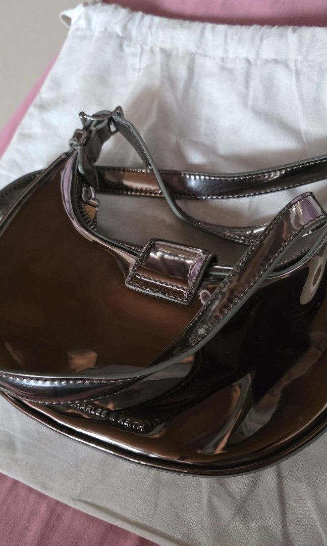 Charles & Keith Metallic Shoulder Bag (Category: Shoulder Bags) located in Santa Maria. Submitted by ellahqy28 (Listing ID 1461190346, Image 2). Description: - Brand: Charles & Keith - Style: Shiny metallic shoulder bag - Design: Unique curved shape - Closure: Silver buckle - Included: Original dust bag - Features: Adds shine to outfits, perfect size for essentials.
