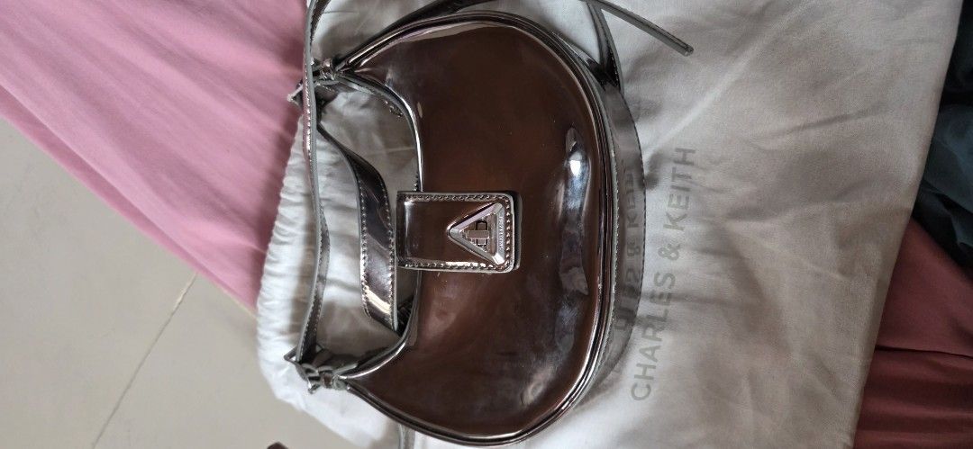Charles & Keith Metallic Shoulder Bag (Category: Shoulder Bags) located in Santa Maria. Submitted by ellahqy28 (Listing ID 1461190346, Image 1). Description: - Brand: Charles & Keith - Style: Shiny metallic shoulder bag - Design: Unique curved shape - Closure: Silver buckle - Included: Original dust bag - Features: Adds shine to outfits, perfect size for essentials.