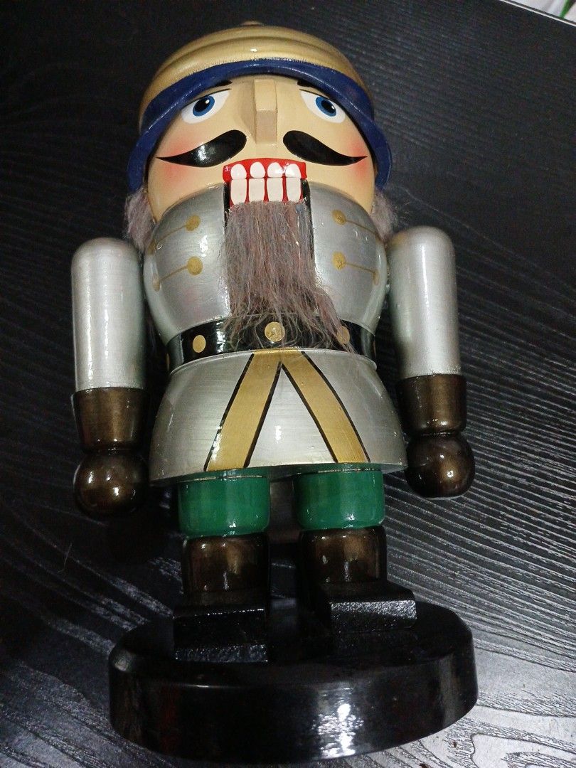 Christmas Soldier (Category: Other Home Decor) located in Davao. Submitted by ferdipt (Listing ID 1461136491, Image 1). Description: A wooden nutcracker figurine designed like a soldier in a silver and gold uniform. It features a blue and gold helmet, green trousers, and synthetic grey hair and beard details. This type of decorative piece is commonly used as a traditional holiday ornament or tabletop display during Christmas..