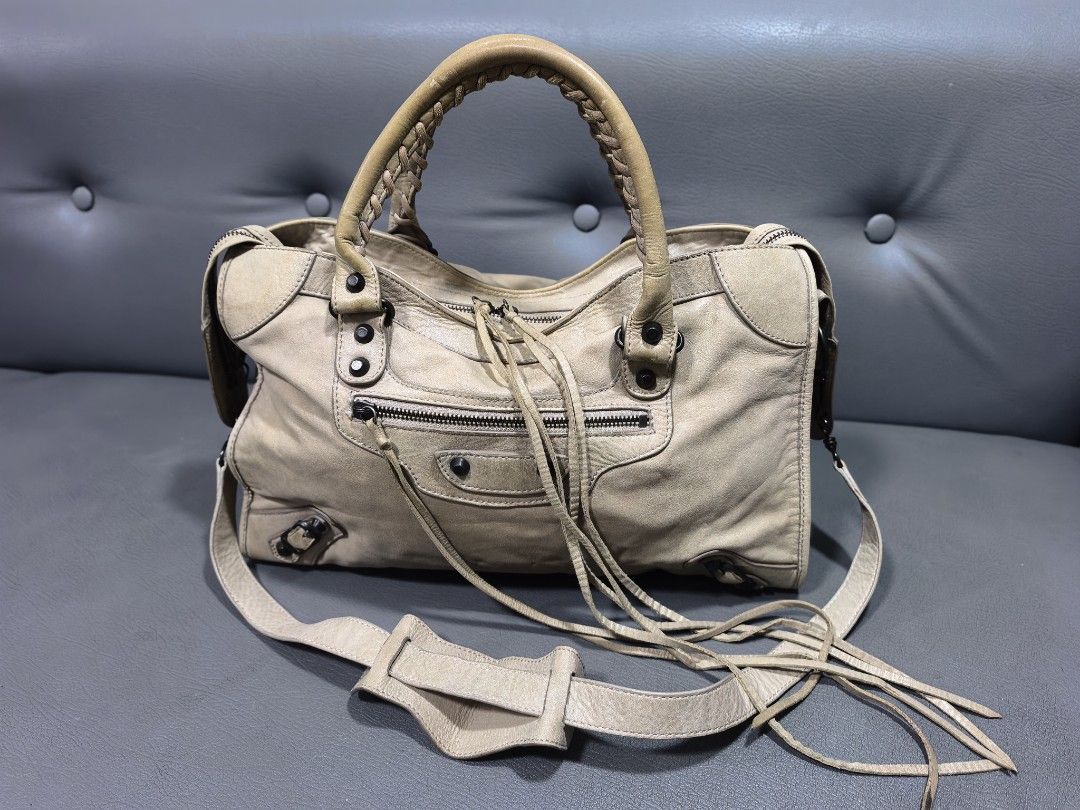 City Bag (not balenciaga) (Category: Luxury Bags & Wallets) located in Cagayan de Oro. Submitted by pootx (Listing ID 1461249259, Image 1). Description: - City bag - Color: Light beige/taupe - Material: Soft leather - Signature buckle details and fringe zipper pulls - Interior: Black fabric with one zip pocket - Includes detachable shoulder strap - Condition: Shows some signs of wear on the leather and handles.