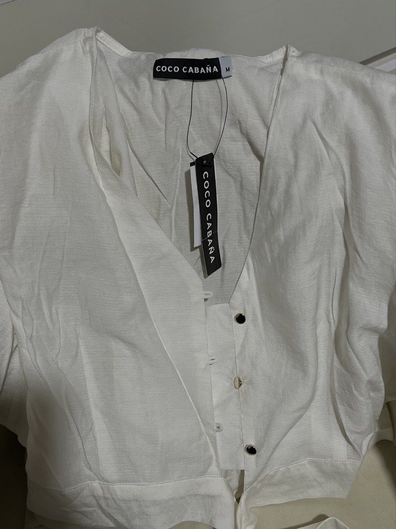 COCO CABANA White Puff Sleeve Tie Front Crop Top (Category: Blouses) located in Las Pinas. Submitted by reiclutter (Listing ID 1461291429, Image 2). Description: - White crop top from COCO CABANA - Features stylish puff sleeves - Chic tie front detail - Functional buttons down the front - Unique textured material - Condition: Brand new. Still with tag. Og price is 599. .