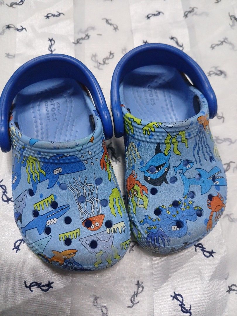 Crocs baby (Category: Babies & Kids Fashion) located in La Trinidad. Submitted by dashopperist (Listing ID 1461226667, Image 2). Description: - Blue Crocs clogs for kids - Fun ocean creature print (sharks, jellyfish, crabs) - Easy slip-on style - Heel strap for secure fit - Crocs logo and size 6 on sole - Ideal for playtime and beach days.