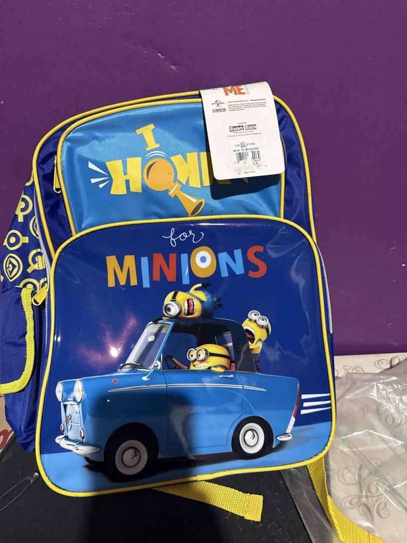 Despicable Me Minions Backpack (Category: Babies & Kids Fashion) located in Manila. Submitted by zealbear_602543 (Listing ID 1461188052, Image 2). Description: - Blue backpack with fun Minions graphic and 'I HONK for MINIONS' text. - Bright yellow straps for a pop of color. - Convenient side mesh pockets for water bottles or small items. - Perfect for school, day trips, or everyday use. - Shows some minor marks on the back straps, as pictured..