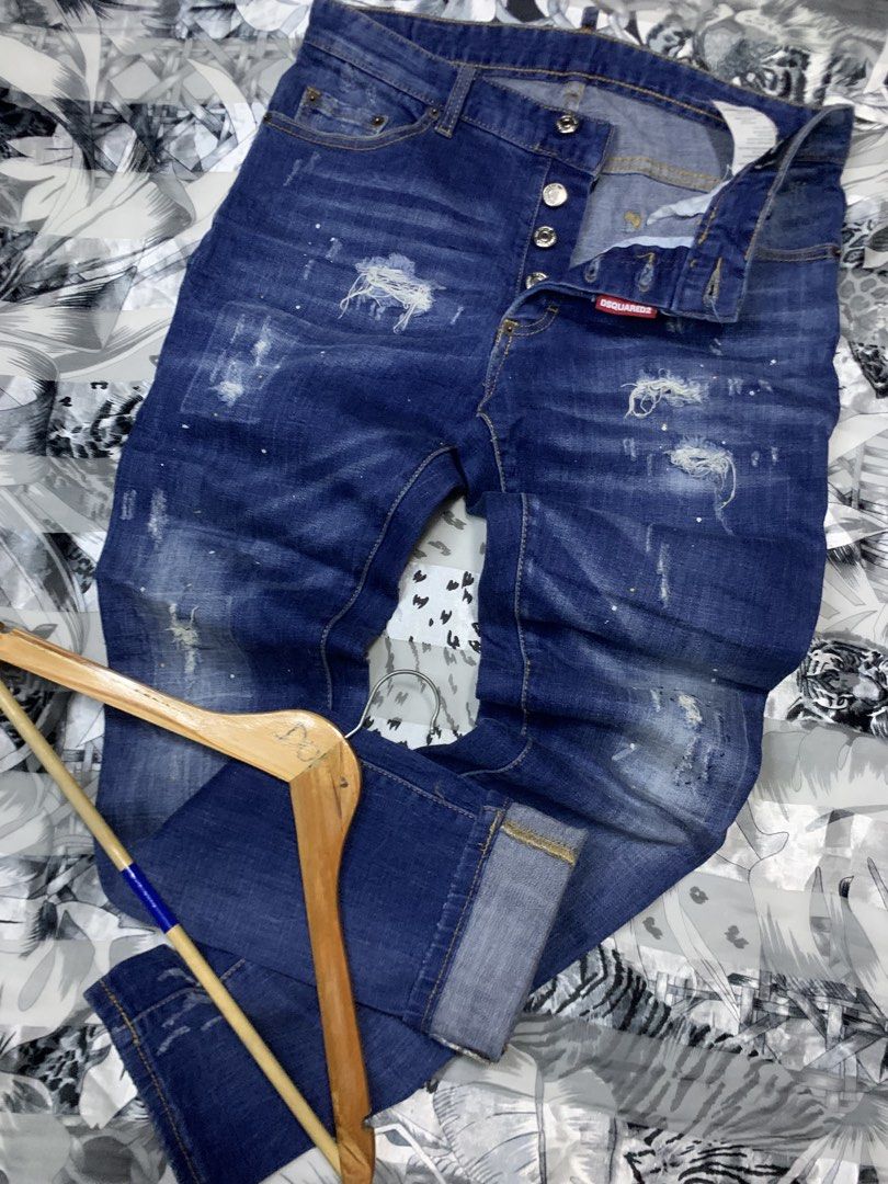DSQUARED2 Blue Distressed Button Fly Jeans (Category: Jeans) located in Polomolok. Submitted by domingthriftclothes (Listing ID 1461260013, Image 2). Description: - Blue DSQUARED2 jeans - Button fly closure - Features distressed details and paint splatters - Rolled cuffs - Ideal for a casual, edgy statement look.