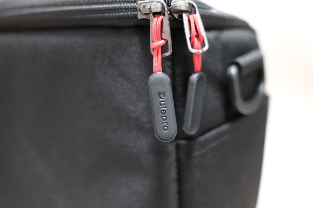 Dulepro Black Camera Bag with Handle (Category: Luxury Bags & Wallets) located in Taguig. Submitted by laluceph (Listing ID 1461144947, Image 3). Description: - Sleek black Dulepro bag - Main zippered compartment for secure storage - Convenient front pocket for quick access - Stylish red cord zipper pulls - Durable top handle for easy carrying - Perfect for carrying a small camera and accessories - Great for travel or everyday adventures.