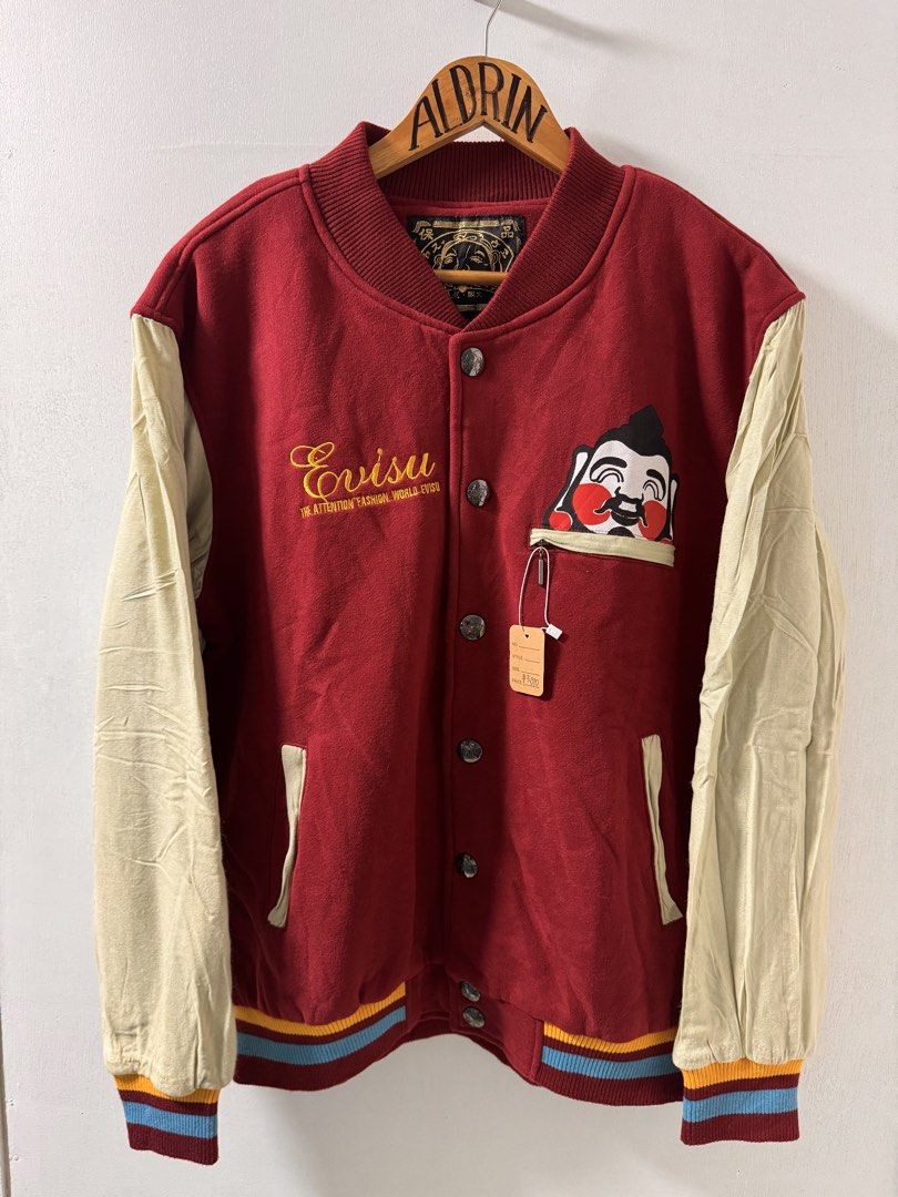 Evisu Varsity Jacket Red/Cream (Category: Coats, Jackets and Outerwear) located in Cavite. Submitted by aldrindela40142 (Listing ID 1461310160, Image 1). Description: - Classic Evisu varsity jacket - Red body with cream sleeves - Iconic Evisu logo and character graphic on front - Ribbed cuffs, collar, and hem - Button-up closure - Ideal for streetwear enthusiasts.