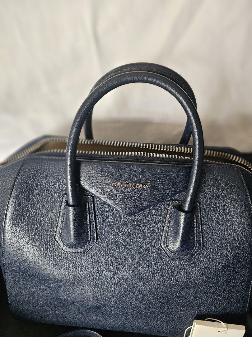 Givenchy Navy Blue Leather Antigona Bag with Strap (Category: Luxury Bags & Wallets) located in Mandaluyong City. Submitted by calibre915 (Listing ID 1461154602, Image 3). Description: - Authentic Givenchy Antigona bag - Color: Navy Blue Leather - Closure: Zip - Features: Embossed Givenchy logo on front - Includes: Original dust bag, authenticity card, detachable navy blue leather strap with silver hardware - Medium.
