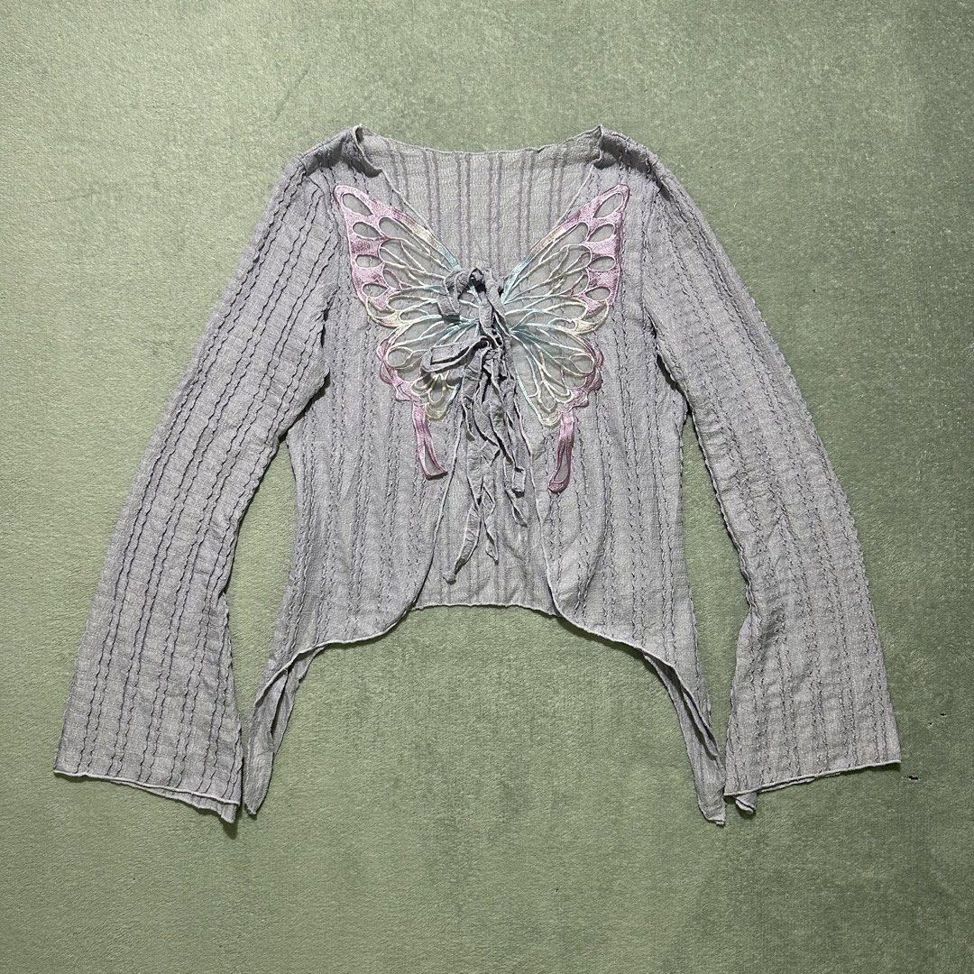 Grey Butterfly Applique Long Sleeve Top (Category: Blouses) located in Bayombong. Submitted by rochelle_archive_garments (Listing ID 1461271631, Image 1). Description: - Grey textured long sleeve top - Beautiful butterfly applique with ribbon details on front - Unique bell sleeves - Cropped, asymmetrical hem - Ties at the front - Size XL.