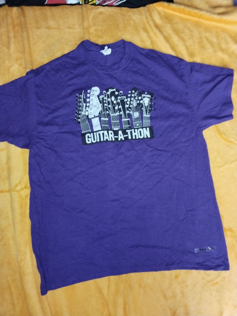 Guitar Tee (Category: Tshirts & Polo Shirts ) located in Mabalacat. Submitted by al_amin_thrift (Listing ID 1461259267, Image 1). Description: Guitar Center Guitar-A-Thon Tee — XL Purple Gildan tee with cool guitar graphic front + full back print featuring Fender, Gibson, Martin, Yamaha, PRS, Ibanez & more! Double-sided, soft cotton, clean music lover's design! • Brand: Gildan Ultra Cotton • Size: XL (L29" × W23") • Color: Purple / White • Featur