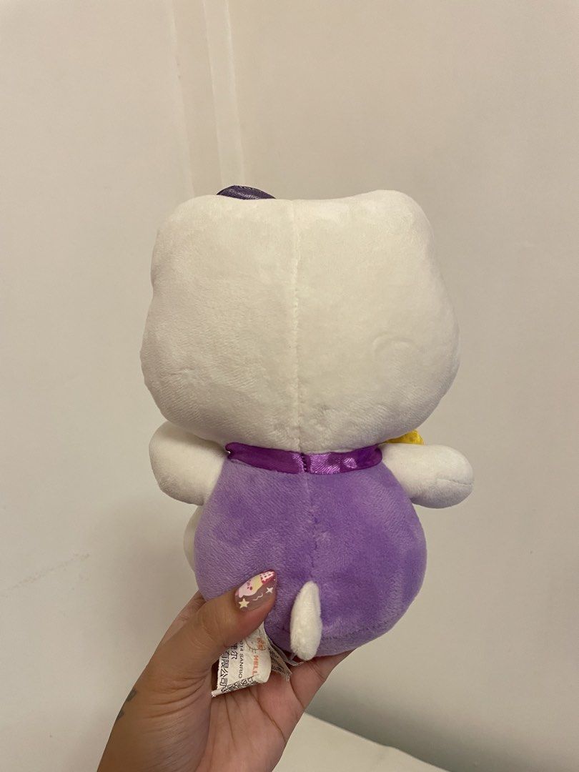 Hello Kitty Plush Toy Purple Outfit (Category: Plushies & Soft Toys) located in Iba. Submitted by wealtheallymari99 (Listing ID 1461115770, Image 2). Description: - Adorable Kitty plush toy - Stands approximately 8 inches tall - Features a cute purple outfit with a yellow accessory - Super soft and cuddly, perfect for hugs! - Ideal for Kitty collectors or as a thoughtful gift - Authentic Sanrio merchandise.