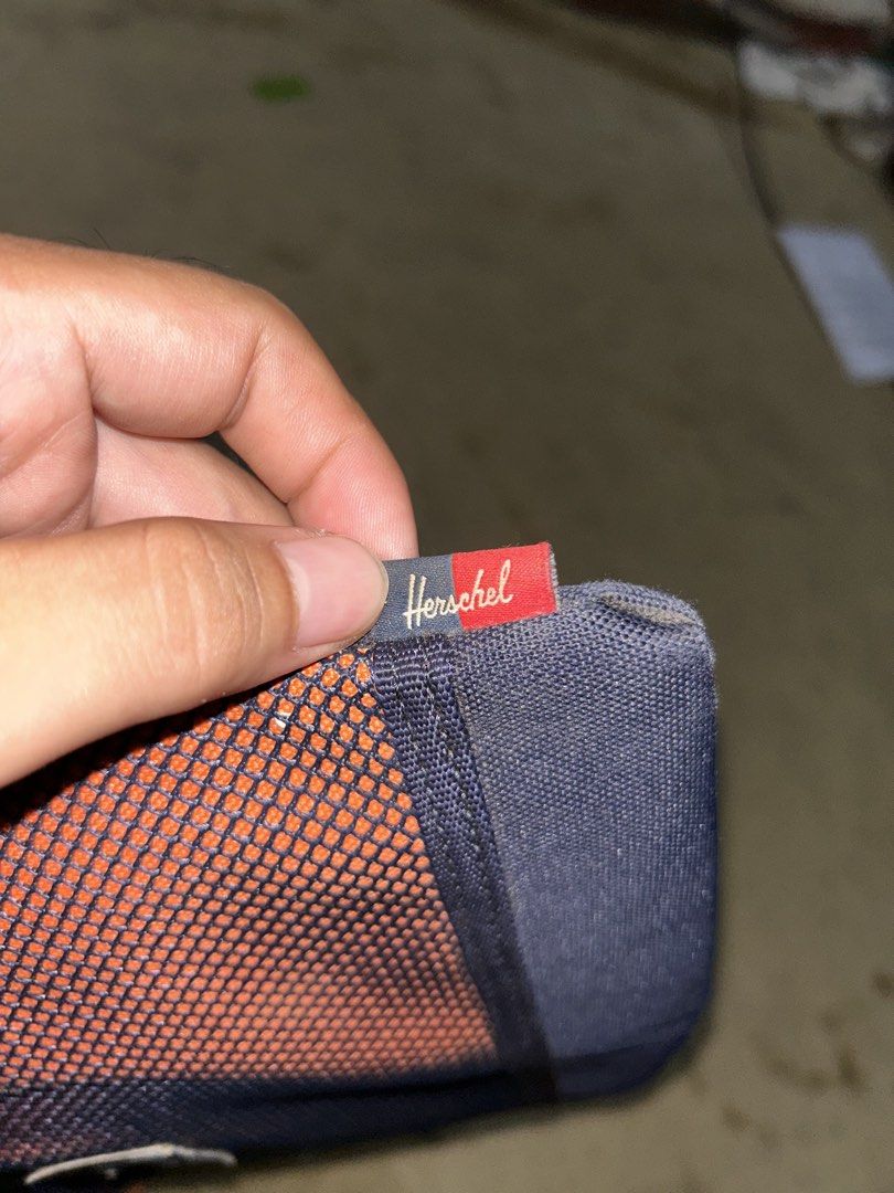 Herschel Supply Co. Crossbody Bag (Category: Cross-body Bags) located in Barotac Nuevo. Submitted by ehsherjohn27 (Listing ID 1461144485, Image 3). Description: - Herschel Supply Co. crossbody bag - Color: Navy blue with orange mesh front panel - "Herschel Supply Company" text detail - Interior "Welcome to Herschel" tag - Adjustable strap for comfortable wear - Secure zipped main compartment.