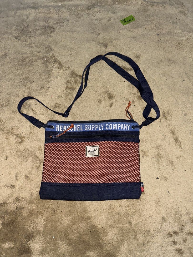 Herschel Supply Co. Crossbody Bag (Category: Cross-body Bags) located in Barotac Nuevo. Submitted by ehsherjohn27 (Listing ID 1461144485, Image 1). Description: - Herschel Supply Co. crossbody bag - Color: Navy blue with orange mesh front panel - "Herschel Supply Company" text detail - Interior "Welcome to Herschel" tag - Adjustable strap for comfortable wear - Secure zipped main compartment.