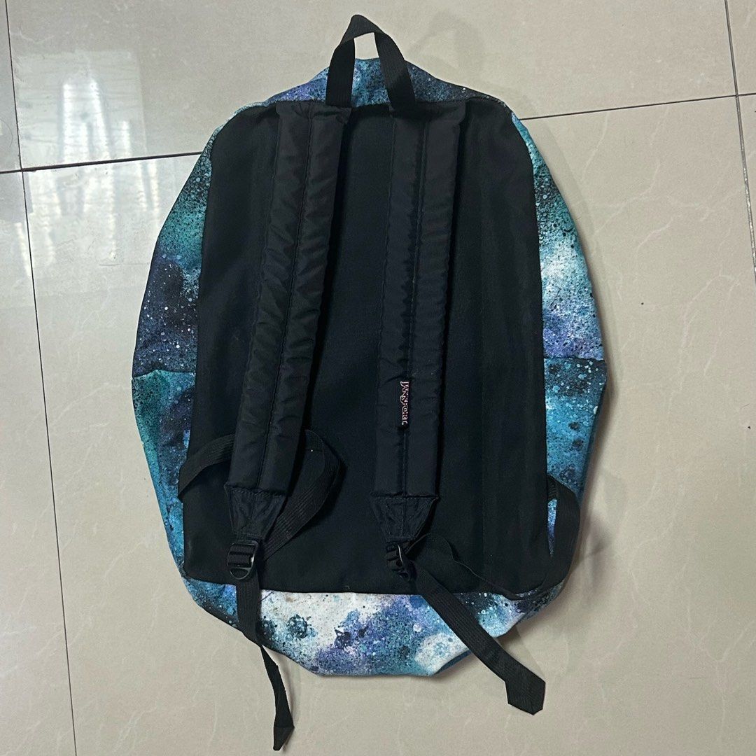Jansport Backpack - Galaxy/Space Print (Category: Backpacks) located in Quezon City. Submitted by stlntno095 (Listing ID 1461144857, Image 2). Description: - Jansport backpack with a galaxy/space print - Features blue and white splatter designs - Includes a main compartment and a front pocket - Adjustable straps for a comfortable fit - Perfect for school or everyday use - Has minor defect (yellowish inner lining).