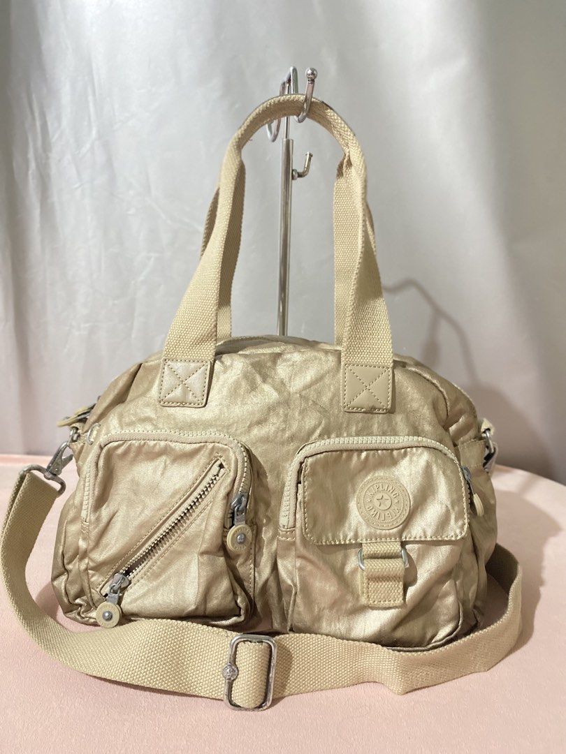 Kipling Metallic Gold Nylon Shoulder Bag (Category: Shoulder Bags) located in Tagum. Submitted by luxeukayfinds_ (Listing ID 1461208528, Image 1). Description: ‼️ CHECK EACH PHOTOS FOR SIGN OF USE‼️ - Stylish gold Kipling bag - Multiple pockets on the front for organization - Adjustable shoulder strap for comfortable carrying - Convenient top handles - Zippers are in good working condition - Ideal size for everyday essentials.