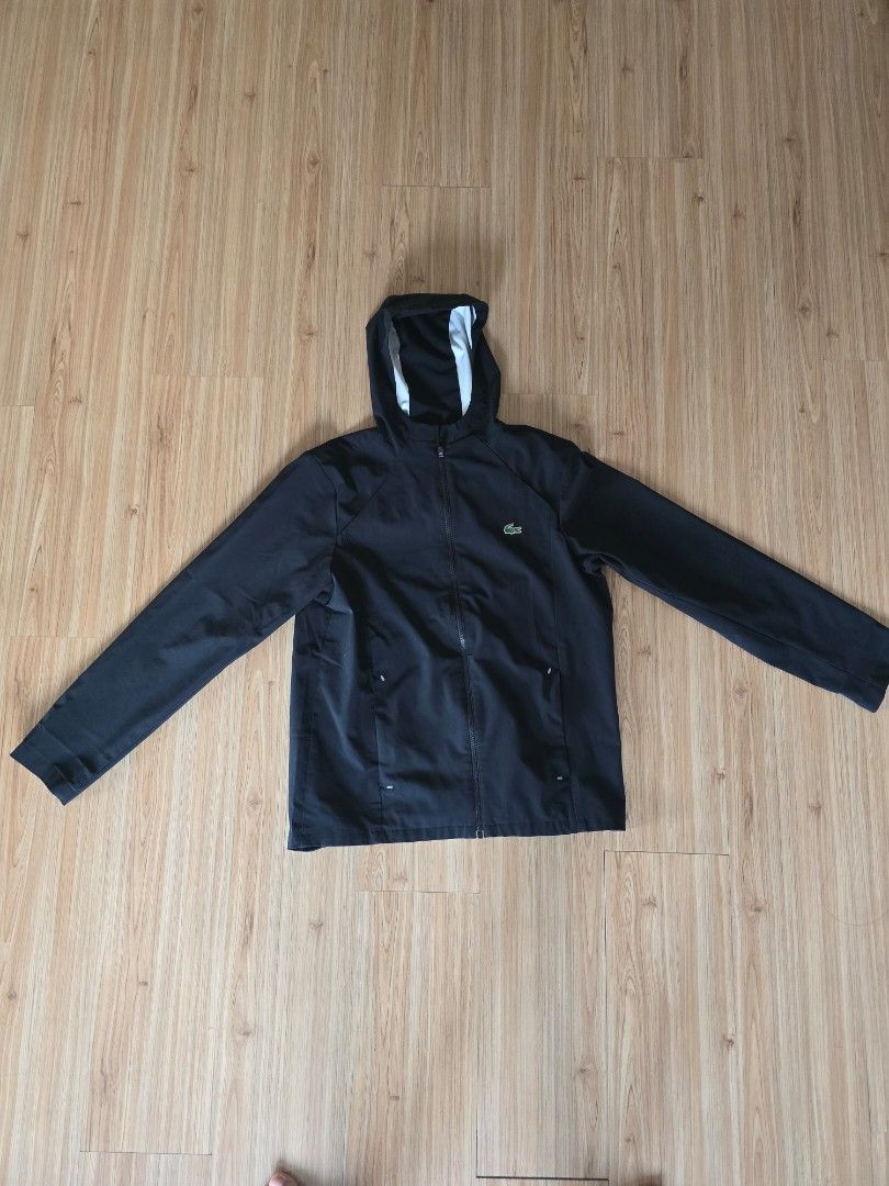 Lacoste Black Hooded Jacket (Category: Coats, Jackets and Outerwear) located in Pasig City. Submitted by yoyosstore (Listing ID 1461190457, Image 2). Description: Personal rain jacket not thrift. Bought bnew. material is stretch fabric like spandex, vwry comfortable. size 52 L - Black hooded jacket from Lacoste (raincoat) fully waterproof - Full zip closure - Iconic crocodile logo on the chest - Two side pockets - Ideal for casual wear or light o