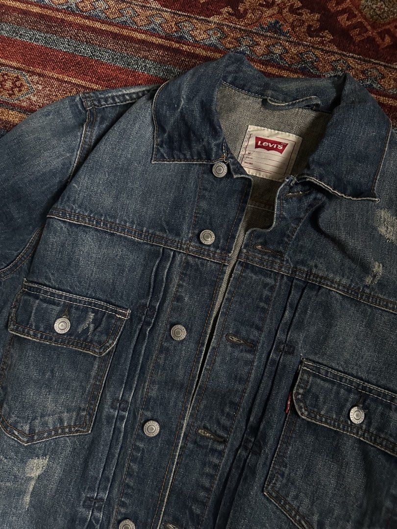 Levi's Denim Jacket Blue Distressed Trucker Style (Category: Coats, Jackets and Outerwear) located in Manila. Submitted by margaretta89487 (Listing ID 1461218150, Image 2). Description: Width: 30-31 L- 32 Classic Levi's denim jacket - Blue wash with distressed details - Two chest pockets with button closures - Button front and cuffs - Standard trucker jacket fit - Ideal for layering.