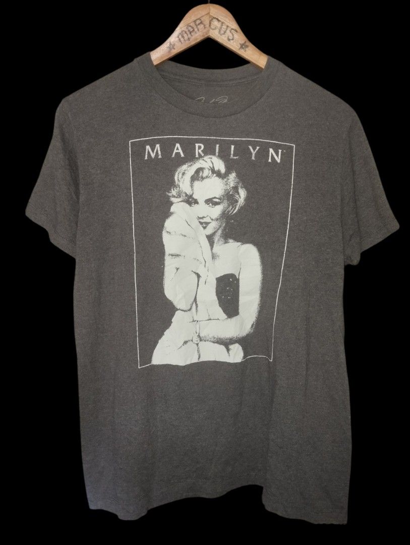 Marilyn Monroe Graphic T-Shirt (Category: Tshirts & Polo Shirts ) located in Manila. Submitted by thriftjepo01336 (Listing ID 1461211733, Image 1). Description: - Grey t-shirt featuring a black and white graphic of Marilyn Monroe. - 'MARILYN' text printed above the image. - Comfortable and stylish design. - Perfect for casual wear or making a statement..
