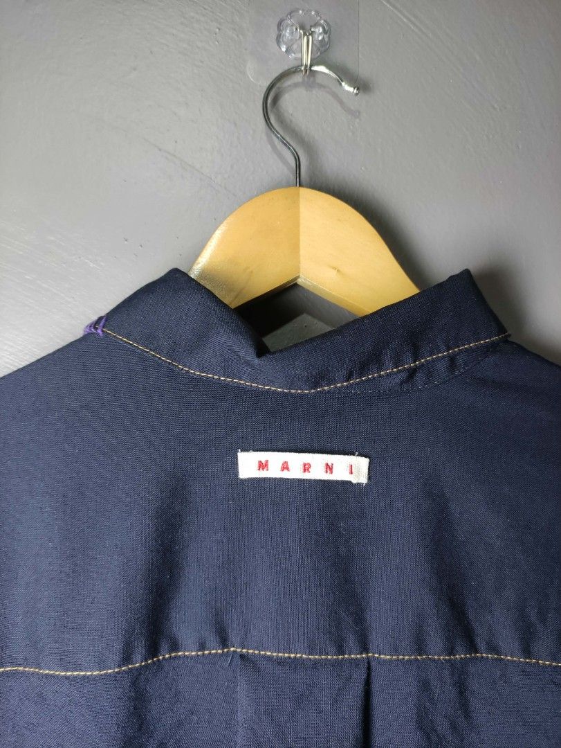 Marni Navy Blue Shirt with Contrast Stitching (Category: Luxury Apparel) located in Batangas. Submitted by andifits.ph (Listing ID 1461294949, Image 3). Description: - Navy blue Marni shirt -Size 38 -"Width 20" Lenght 27" No issue - Features contrast stitching throughout - Two chest pockets with button closures - Button-up front - Embroidered details on collar and chest pocket - Long sleeves with button cuffs - Ideal for casual or smart-casual ou