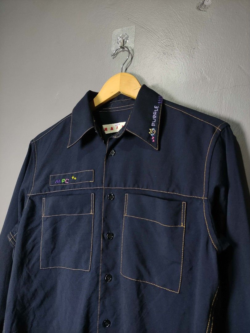 Marni Navy Blue Shirt with Contrast Stitching (Category: Luxury Apparel) located in Batangas. Submitted by andifits.ph (Listing ID 1461294949, Image 2). Description: - Navy blue Marni shirt -Size 38 -"Width 20" Lenght 27" No issue - Features contrast stitching throughout - Two chest pockets with button closures - Button-up front - Embroidered details on collar and chest pocket - Long sleeves with button cuffs - Ideal for casual or smart-casual ou