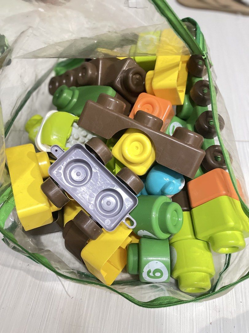 Mega Bloks Building Blocks Toy Set (Category: Lego & Building Sets) located in Quezon City. Submitted by prelovedclotheskimukays (Listing ID 1461266883, Image 1). Description: - Bag of Mega Bloks building blocks - Assorted colors (yellow, brown, green, orange) and shapes - Includes a green car and a grey base piece - Encourages creative play and building - Plenty of pieces for extended entertainment - Ideal for young builders.