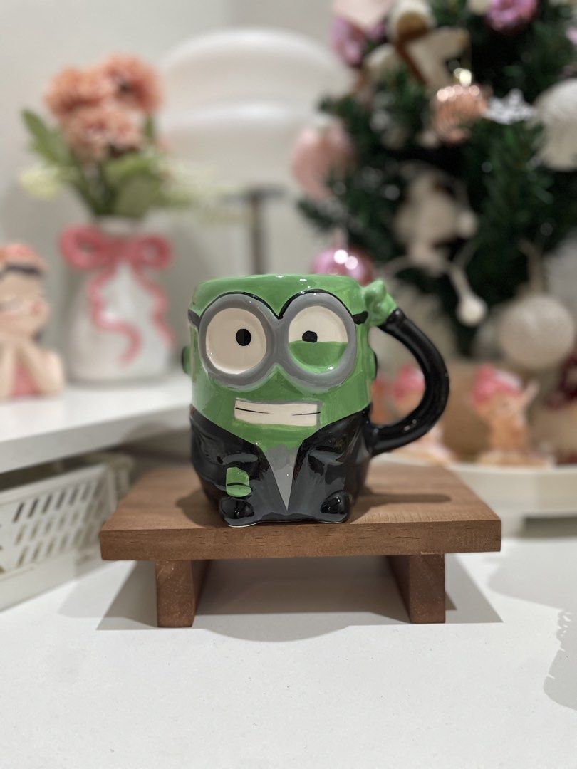 Minion Mug with Suit Design (Category: Coffee & Tea Tableware) located in Quezon City. Submitted by mugs.meowph (Listing ID 1461289761, Image 1). Description: - Adorable Minion mug featuring a stylish suit design. - Perfect for coffee or tea lovers. - Adds a fun and unique touch to your kitchen or desk. - Can be used for everyday drinks or as a decorative display piece. - Features a green mug with black and grey accents. - The handle is a contras