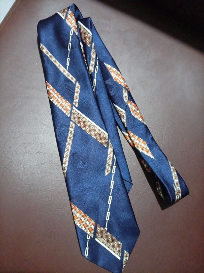 Navy Blue Silk Tie with Geometric Pattern (Category: Ties) located in Manila. Submitted by tinygazo90639 (Listing ID 1461266238, Image 1). Description: - Classic navy blue silk tie - Features a repeating geometric pattern in white, orange, and tan - Ideal for formal occasions or adding a touch of class - Approximately 57 inches long.