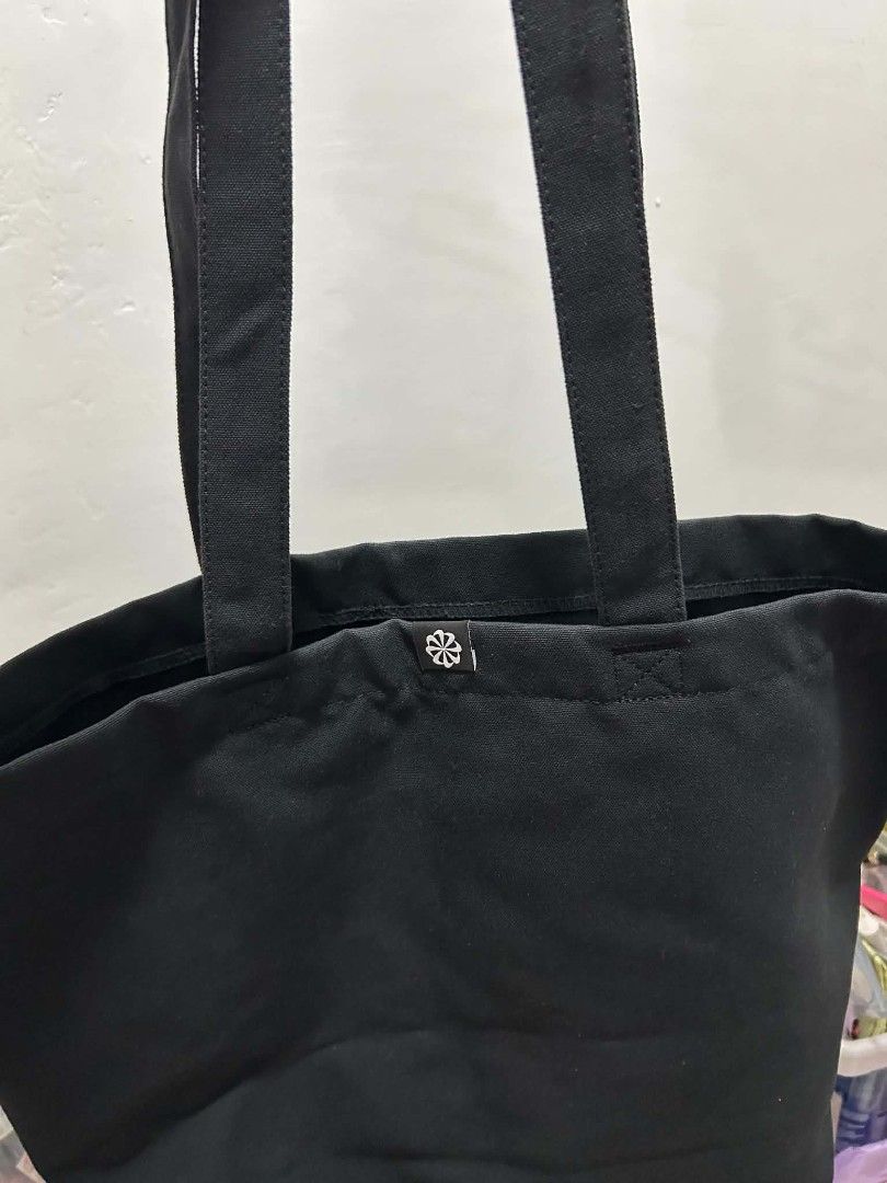 Nike Black Canvas Tote Bag (Category: Tote Bags) located in San Pablo. Submitted by anechka1823 (Listing ID 1461233223, Image 1). Description: - Brand: Nike - Type: Black Canvas Tote Bag - Features: Spacious interior, ideal for everyday use - Design: Iconic Nike swoosh logo - Extra Detail: Small flower-like logo near the top.