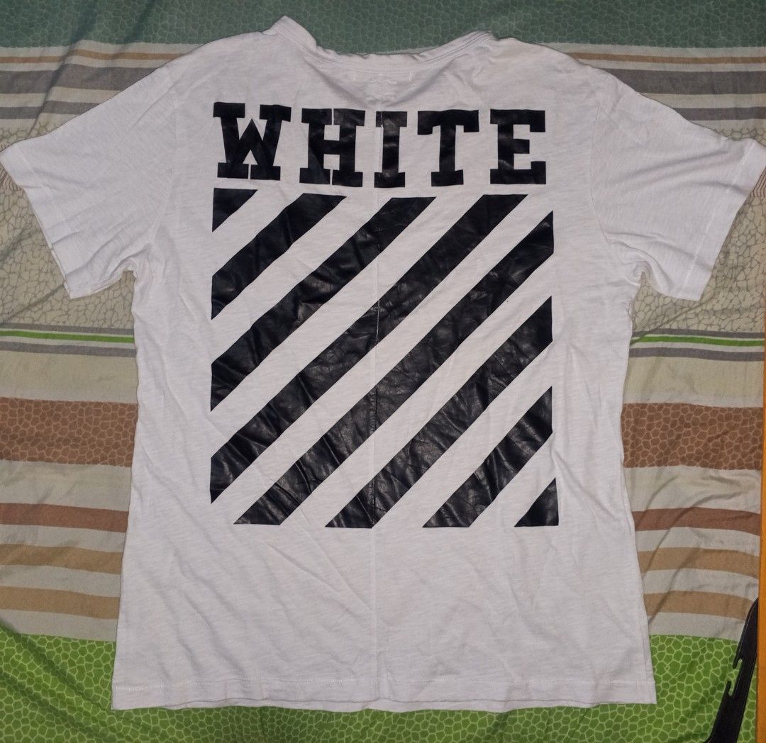 Off-White White T-Shirt Diagonal Stripe Graphic (Category: Tshirts & Polo Shirts ) located in Magalang. Submitted by zeiansoria64090 (Listing ID 1461235818, Image 2). Description: - Off-White t-shirt -L-xl - Features iconic diagonal stripe graphic on the back - 'WHITE' text prominently displayed on front and back - Perfect for everyday casual wear - Tag shows Off-White branding.