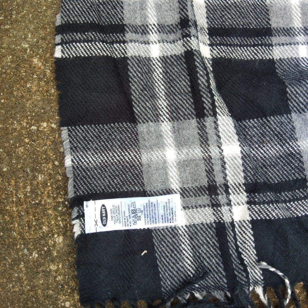 Old Navy Plaid Scarf (Category: Scarves) located in Tanza. Submitted by ThriftPieces (Listing ID 1461223113, Image 2). Description: - Classic black, white, and grey plaid pattern - Soft material with fringe details - Brand: Old Navy - Approx. 60 inches long - Perfect for adding a stylish pattern to your look.