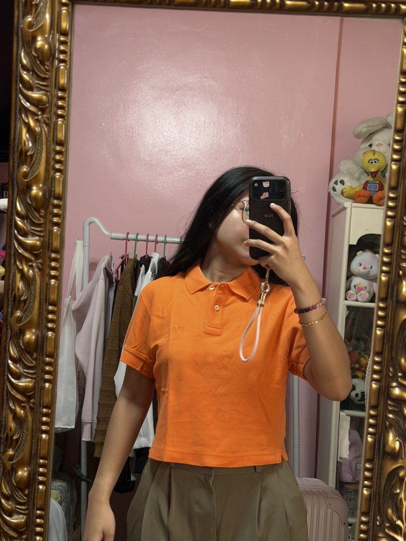 Orange Cropped Polo Shirt (Category: Tshirts & Polo Shirts ) located in Manila. Submitted by mongosoleigh (Listing ID 1461262027, Image 1). Description: - Cute orange cropped polo shirt - Short sleeves with collar and button closure - Small embroidered logo on chest - Versatile: pairs well with high-waisted pants or skirts - Comfortable and stylish for everyday wear.
