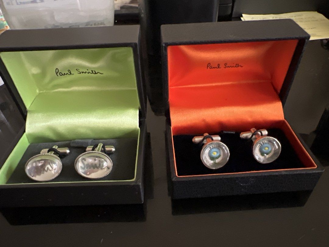 Paul Smith Cufflinks - Two Pairs (Category: Cuff Links) located in Manila. Submitted by mikimae777 (Listing ID 1461168413, Image 1). Description: - Authentic Paul Smith cufflinks - Two distinct styles available: - Engraved 'Paul Smith' on oval stones - Blue flower design under glass - Both pairs come with original Paul Smith boxes - Ideal accessories to complete your formal wear.