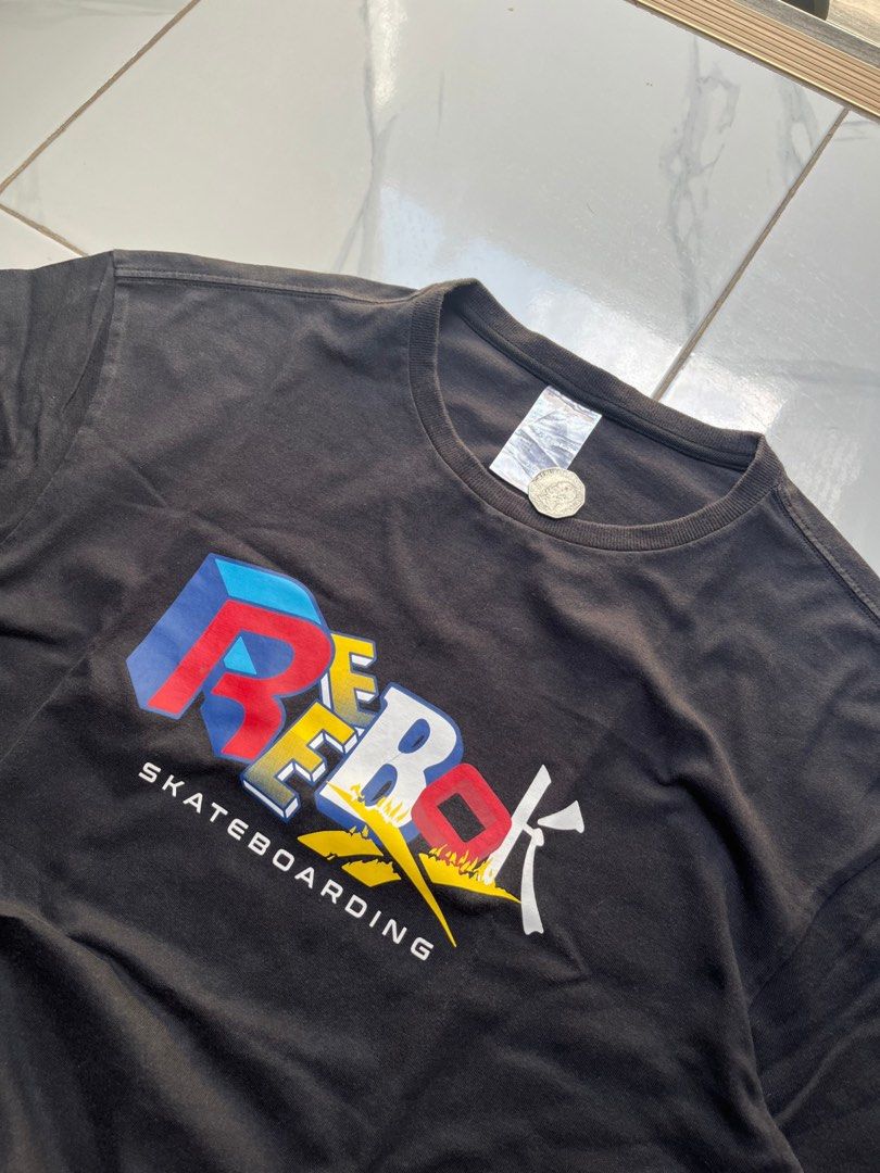 Reebok Skateboarding Printed Tee (Category: Tshirts & Polo Shirts ) located in Manila. Submitted by chalkzone20 (Listing ID 1461297468, Image 2). Description: - Black Reebok Skateboarding T-shirt - Features classic Reebok logo with 'Skateboarding' text - Size: Medium (fits like a Large) - Measurements: 22 inches (width) x 31 inches (length) - Note: Minor line on the print - Color may vary slightly due to lighting.