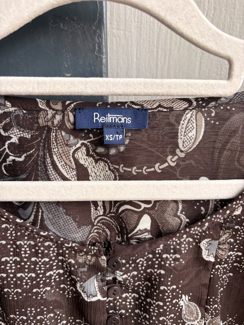 Reitmans Brown Floral Sheer Button-Up Blouse XS/TP (Category: Blouses) located in Cainta. Submitted by declutteringprelovedbyzelle (Listing ID 1461242721, Image 2). Description: - Brand: Reitmans - Color: Brown - Pattern: Floral print - Style: Sheer blouse - Sleeves: Short with ruffled cuffs - Closure: Button-up front - Waist: Drawstring - Fabric: Lightweight and airy - Versatile: Great for layering or wearing alone.