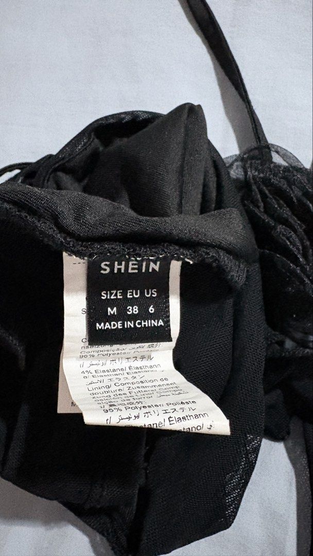 SHEIN Black Sheer Mesh Wrap Tie Top Size M (Category: Blouses) located in Iloilo. Submitted by kathiesboutique.ilo (Listing ID 1461321216, Image 2). Description: - SHEIN black sheer mesh top - Size: Medium (M) - Style: tube with long tie straps - Details: Ruffled sleeves and a flower detail near the neck tie.