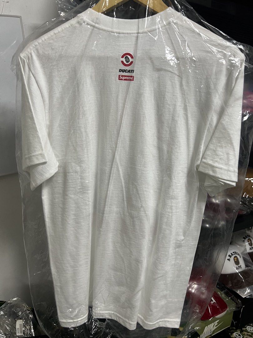 Supreme Ducati White T-Shirt (Category: Tshirts & Polo Shirts ) located in Cavite. Submitted by ziicollections (Listing ID 1461254257, Image 2). Description: - Authentic Supreme x Ducati collaboration t-shirt. - Features a striking graphic print on the front. - Showcases logos prominently on the back. - Perfect for fans of Supreme, Ducati, or both. - A unique and collectible piece. -size :small on tag fit to medium - dimension 19 width x 27 lengt