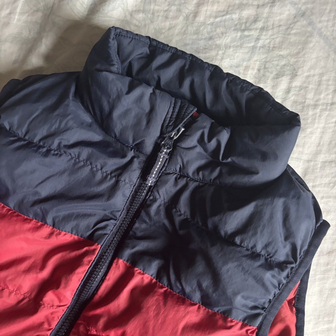 Uniqlo Kids Puffer Padded Warm Vest (Category: Coats, Jackets and Outerwear) located in Binan City. Submitted by myprelovedhaul (Listing ID 1461217708, Image 3). Description: Fits adult xs frame The item in the image is a Uniqlo Kids Light Warm Padded Puffer Vest. It features a distinctive two-tone colorblock design with a dark navy/black shoulder yoke paired with a bold red lower body..