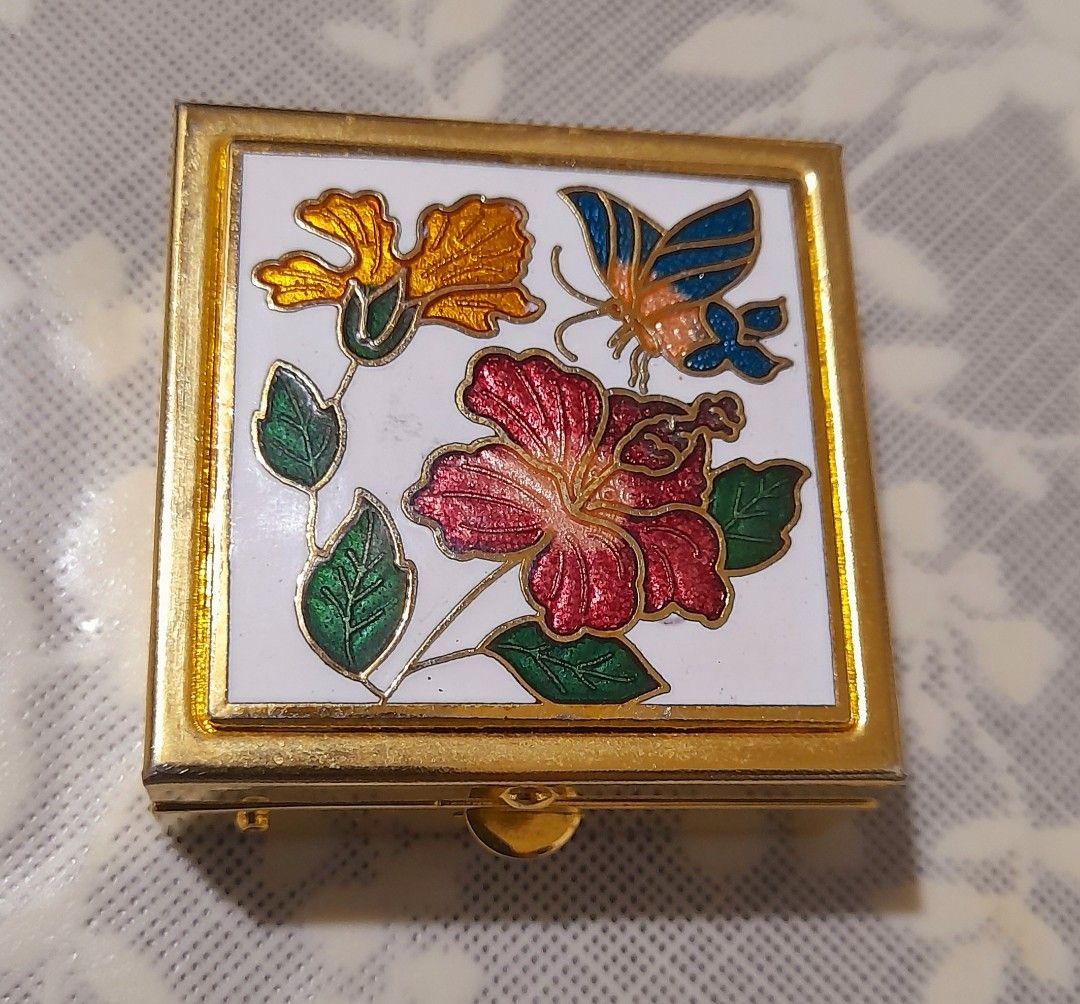 Vintage Cloisonnè Enamel Trinket Box (Category: Other Home Decor) located in Manila. Submitted by miamiga (Listing ID 1461226554, Image 2). Description: Size: 1.5" (L) × 1.5" (W) × 0.5" (H) - Square gold-tone trinket box - Decorated with cloisonnè flowers and a butterfly - With removable container inside - Ideal for pills, mints, or other tiny keepsakes - Compact and portable design - Secure clasp closure - With visible scratches.