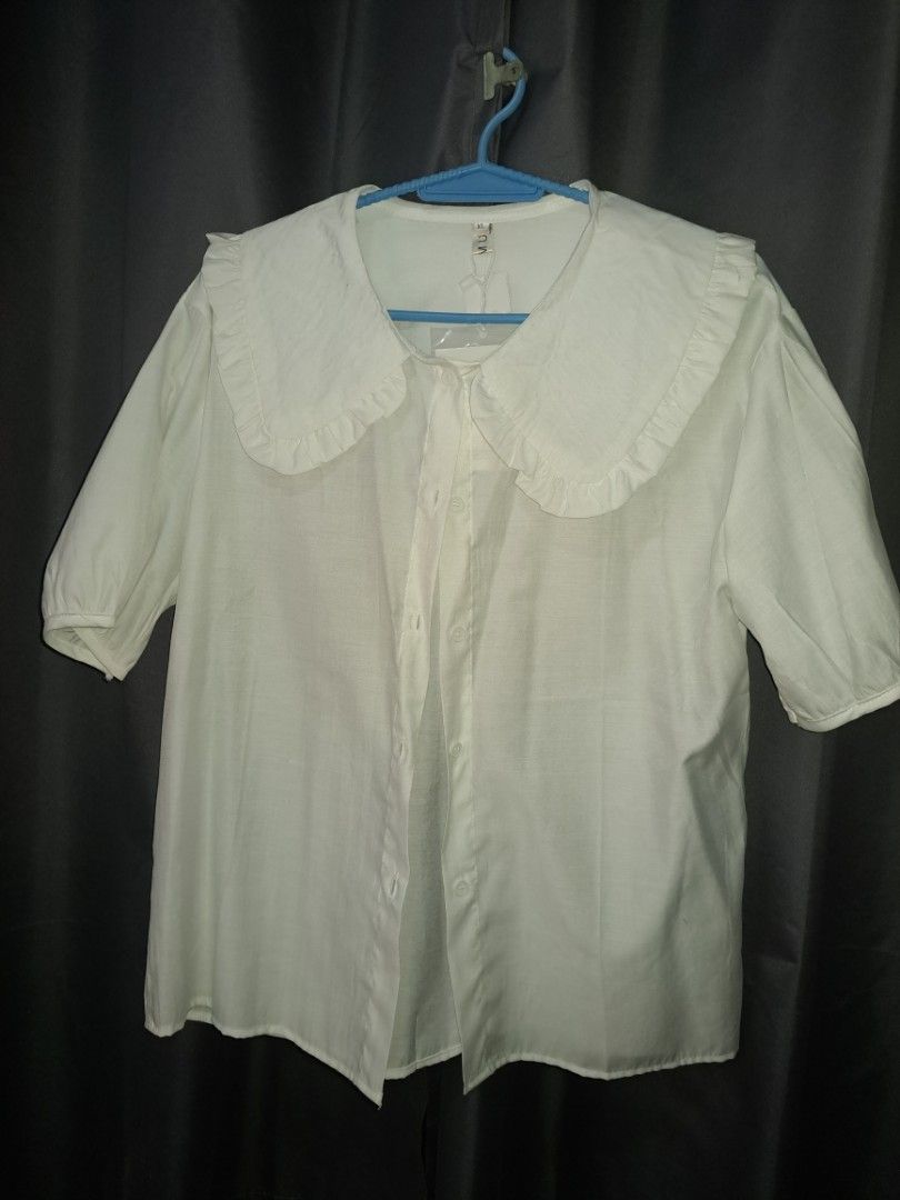 White Button-Up Blouse with Peter Pan Collar (Category: Blouses) located in Cabuyao City. Submitted by _closetbysue (Listing ID 1461139957, Image 1). Description: - White button-up blouse - Features a cute ruffled Peter Pan collar - Short sleeves - Estimated size: XL - Ideal for casual wear or layering - Classic and simple design.