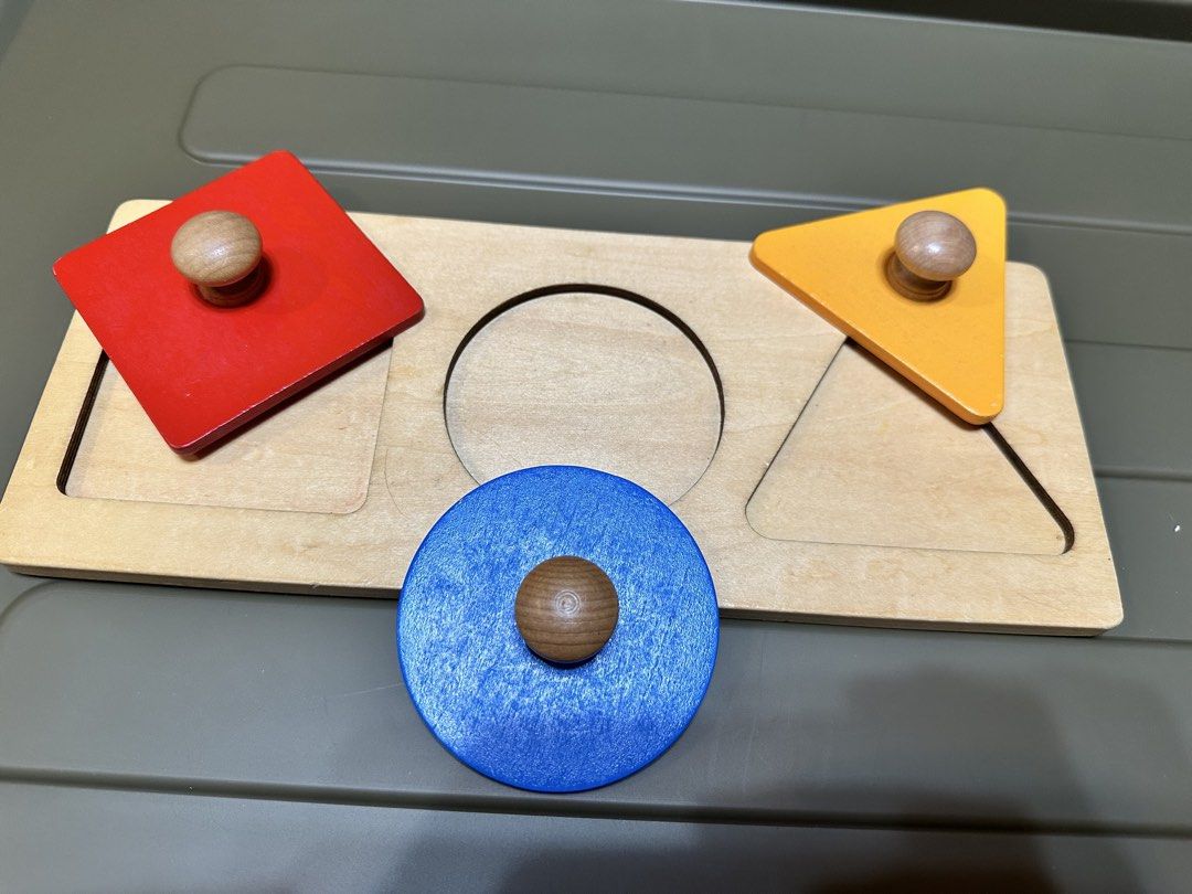 Wooden Shape Sorter Puzzle - Triangle, Circle, Square (Category: Educational & Learning Toys) located in Manila. Submitted by silver.truemountain (Listing ID 1461245027, Image 2). Description: - Classic wooden shape sorter toy. - Includes red square, blue circle, and orange triangle. - Features easy-to-grip wooden knobs for little hands. - Perfect for teaching shapes and colors. - Made with sturdy, durable wood construction. - A fun and education