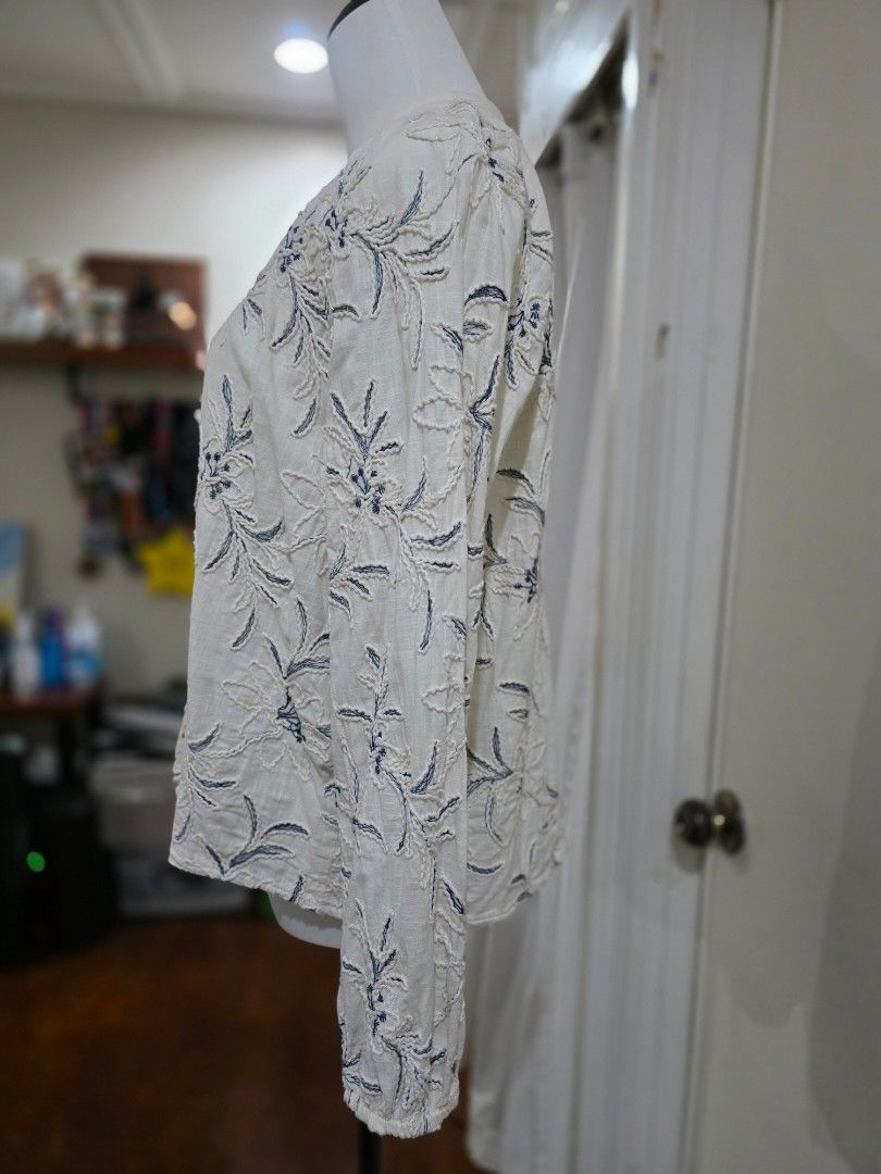 ZARA Embroidered Button-Up Blouse (Category: Blouses) located in Quezon City. Submitted by sec0nd.st0ry (Listing ID 1461224379, Image 3). Description: - Cream colored blouse with beautiful blue floral embroidery - Long sleeves with comfortable elastic cuffs - Button-up front adorned with unique wooden bead details - Lightweight and versatile fabric, perfect for layering or standalone wear - Brand: Zara - Size: Medium.